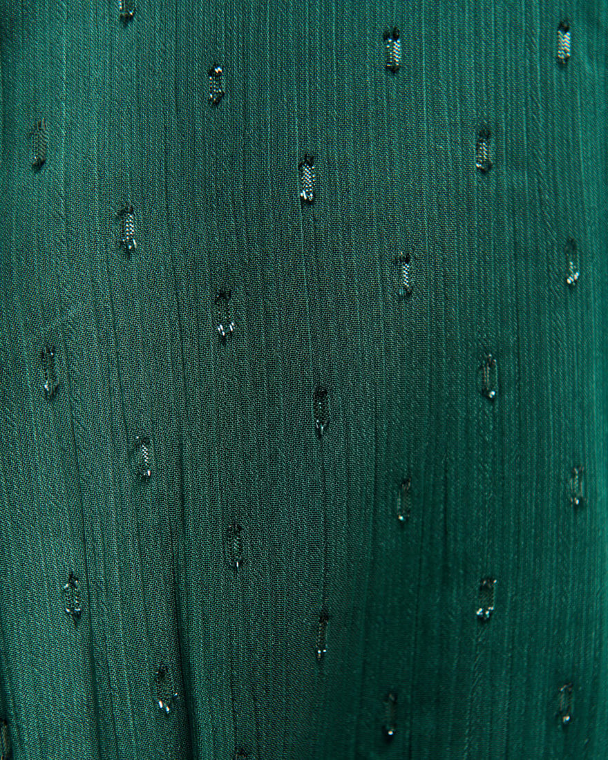 Close-up of a textured green fabric with small black patterns