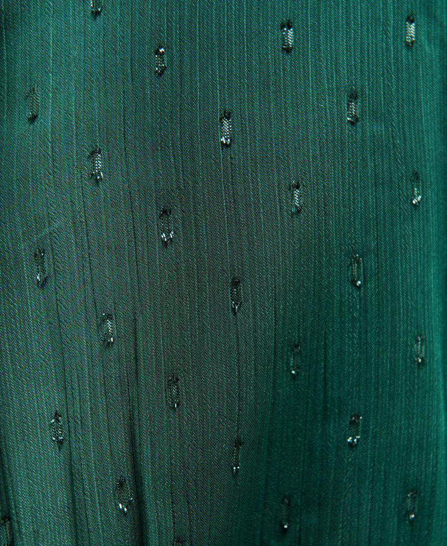 Close-up of a textured green fabric with small black patterns