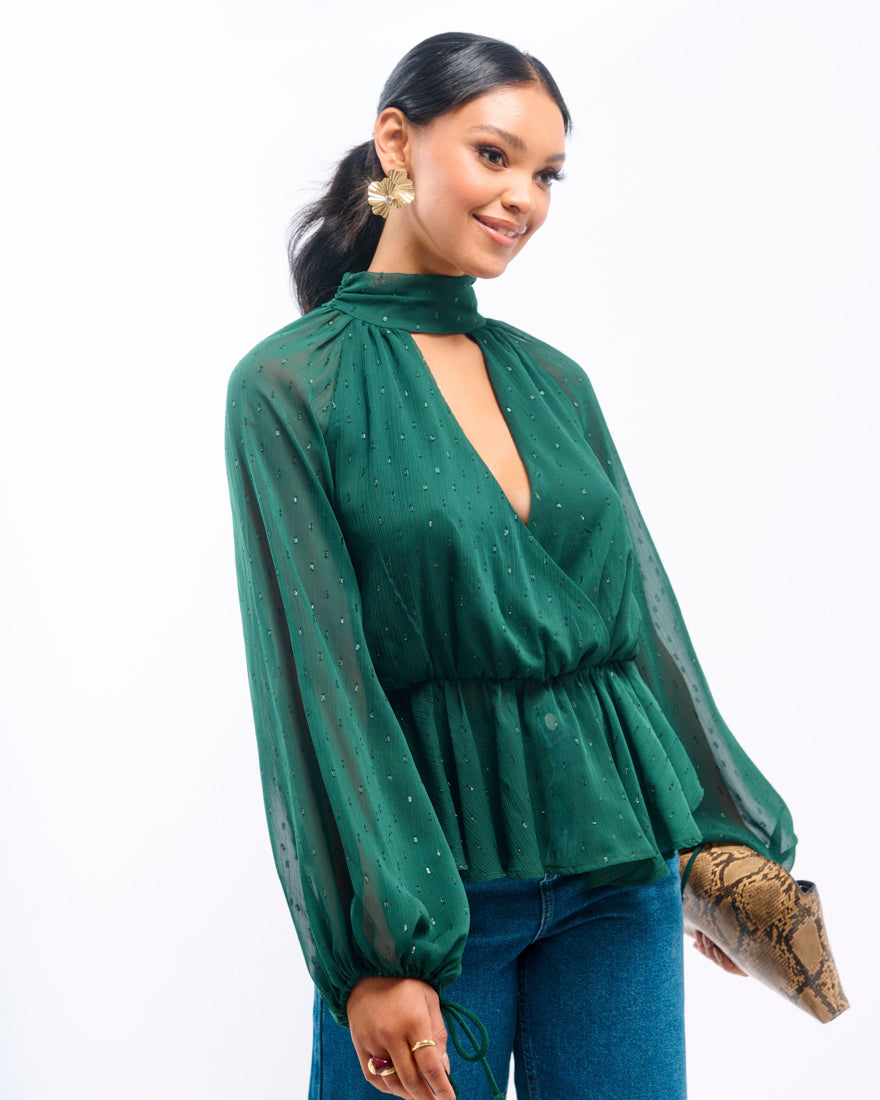 Woman wearing a green blouse with sheer sleeves on a white background