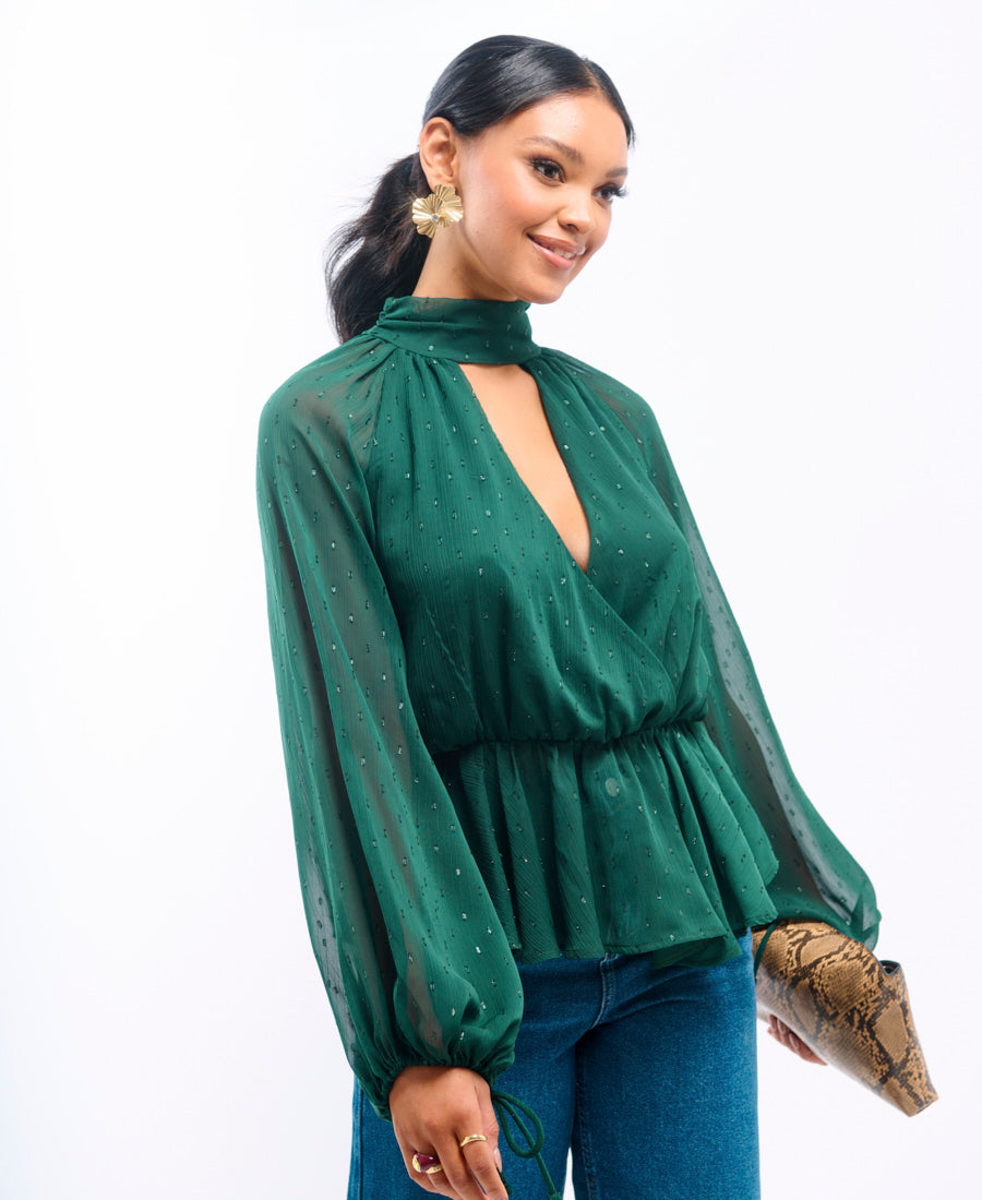 Woman wearing a green blouse with sheer sleeves on a white background