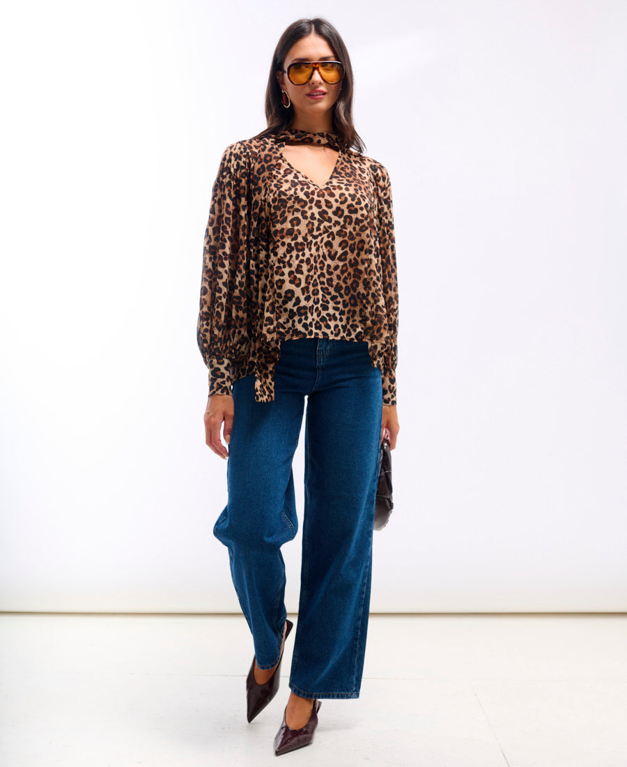 Woman wearing a leopard print top and blue jeans on a white background