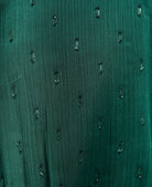 Close-up of a textured green fabric with small black patterns