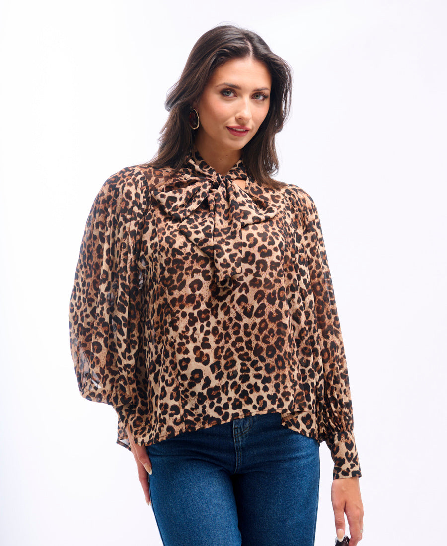 Woman wearing a leopard print blouse and blue jeans on a white background